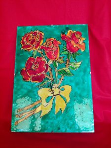 obraz malowany na szkle w kolorach niebiesko-czerwono-żółtym, na bordowym tle, bukiet z czterech czerwonych róż z żółtą kokardą
